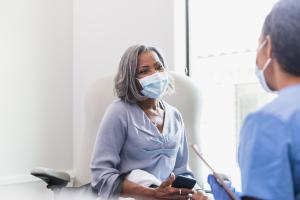 An urgent care doctor speaking with a masked elderly patient at a walk-in urgent care center